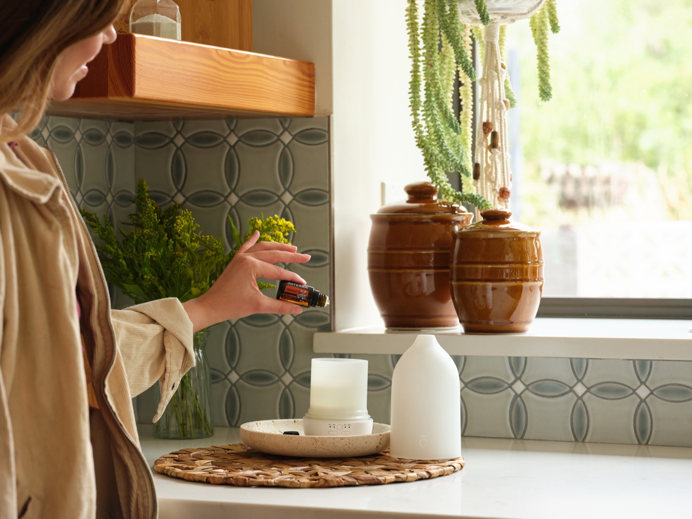 Adding a drop of Harvest Spice to a diffuser on a kitchen windowsill